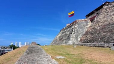 Saint Philippe Kalesi önünde bayrak sallanıyor, Castillo San Felipe de Barajas. Cartagena manzaralı modern gökyüzü tarihi şehir merkezi ve tatil köyü yakınlarındaki