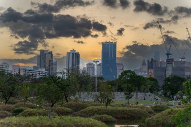 Şehir merkezinde bulutlu gün batımına karşı park