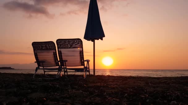 Dua Beach Chairs dan Parasol Silhouettes di Serene Sunrise Sunlight, Static View — Stok Video