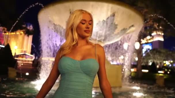 美丽的年轻女子 有着长长的金发 夜晚在喷泉前 动作缓慢 — 图库视频影像