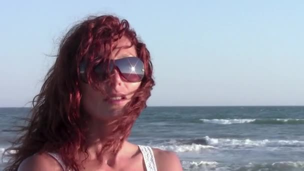Retrato de una hermosa mujer en gafas de sol en una playa — Vídeos de Stock