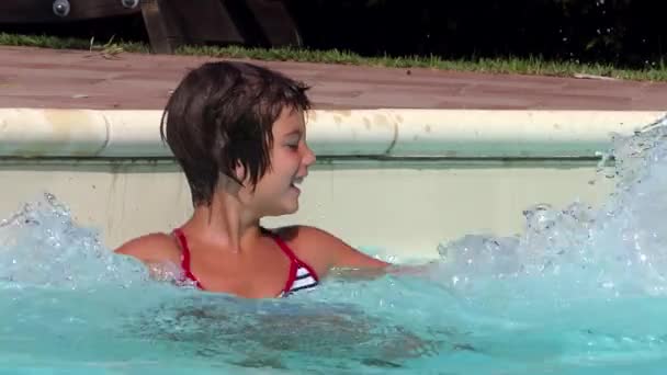 Jong meisje spetteren in het zwembad, slow-motion — Stockvideo