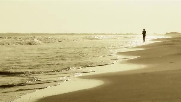 Hombre corriendo en la playa al atardecer — Vídeo de stock