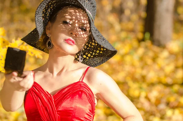 Portrait of female caucasian with shadow pattern from hat on face holding a mirror — Stock Photo, Image