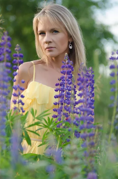 Young beautiful woman in the lupine field — Stock Photo, Image