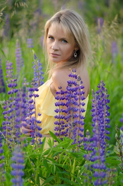 Young beautiful woman in the lupine field — Stock Photo, Image