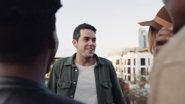 Adult Caucasian Male and Caucasian female socialising with a diverse group of friends at rooftop party. Chatting lightheartedly at sunset. High quality image. — Stock Video
