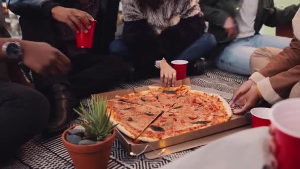 Grupo diverso de amigos adultos que comem pizza e bebem em um telhado na luz da tarde. Imagens 4K de alta qualidade — Vídeo de Stock