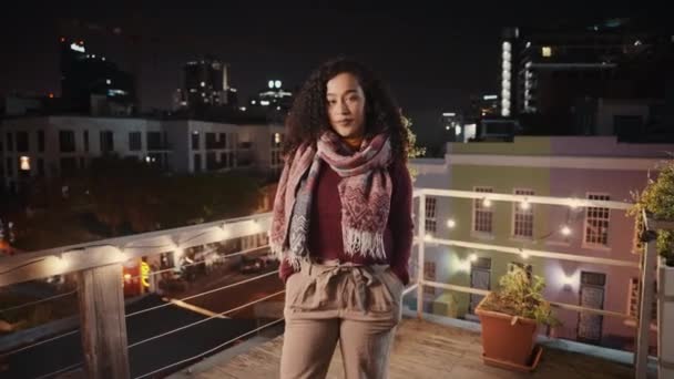 Giovane donna di razza mista in piedi, sorridente e ridente ad una festa sul tetto durante la notte. — Video Stock