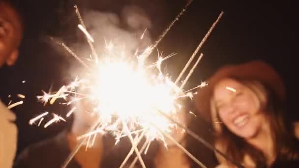 Мульти-этническая группа друзей празднует зажигая свои искры на открытом воздухе в ночное время. Высококачественные 4К кадры — стоковое видео