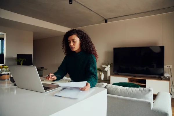Adulto multicultural feminino estressado, trabalhando no laptop sentado na bancada da cozinha com papéis — Fotografia de Stock