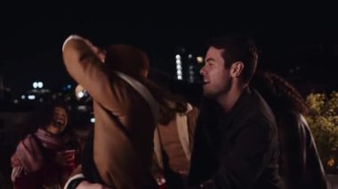 Beyaz erkek ve kadın şehrin çatı katındaki bir partide dans ediyorlar.