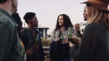 Bir grup etnik çeşitliliğe sahip arkadaş çatıda durup akşamları kutlama ve sosyalleşme yapıyorlar. Yüksek kalite 4K görüntü
