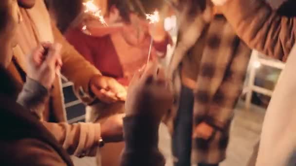 Grupo multiétnico de amigos adultos bailando con bengalas en una azotea con la ciudad detrás de ellos en la noche. — Vídeo de stock