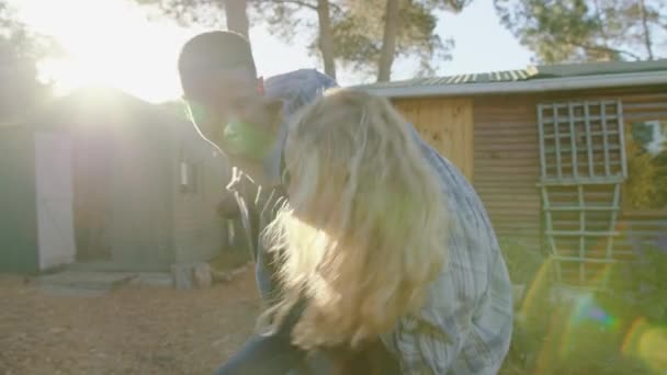 Gemengd ras gelukkig paar rijden op piggy rug doorgegeven houten huisje — Stockvideo