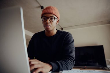 Laptopuyla evde çalışan Afro-Amerikalı bir erkek. Afrikalı Amerikalı erkek kalemle kağıda notlar yazıyor. Yüksek kalite fotoğraf