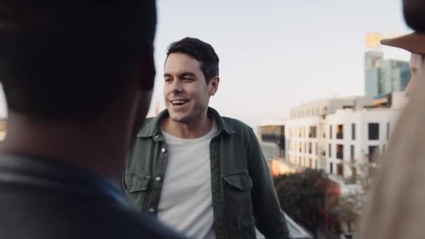 Adult Caucasian Male socializing with a diverse group of friends at rooftop party. Chatting lightheartedly at sunset. High quality image. — Stock Video