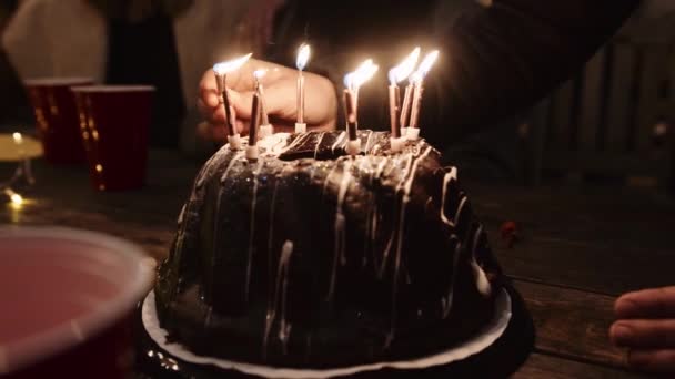 Кавказький самець запалює свічки торта для дня народження вночі. — стокове відео