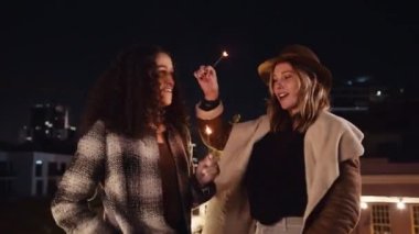 Beyaz ve çok kültürlü bir kadın gecenin bir yarısı çatıdaki bir partide maytaplarla dans ediyor. Yüksek kalite 4K görüntü
