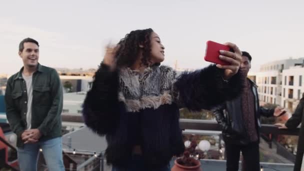 Kvinna ringer en grupp vänner för att ta en selfie på en smarttelefon utomhus på ett tak. Högkvalitativ 4K-film. — Stockvideo
