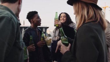 Bir grup çok ırklı arkadaş çatıda bir çember oluşturarak tezahürat yapıyor ve akşamları sosyalleşiyorlar. Yüksek kalite 4K görüntü