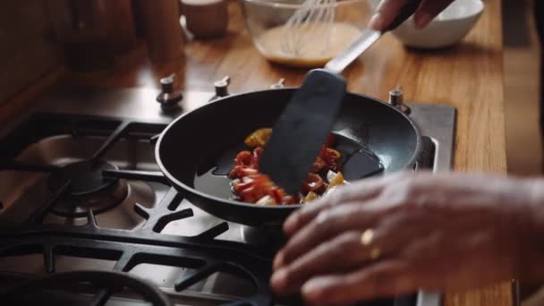 Närbild av händer, äldre mångkulturella par steka grönsaker i en kastrull på spisen i köket — Stockvideo