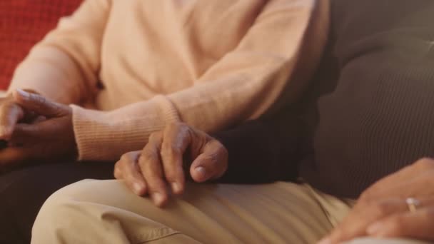 Multikulturella äldre par som håller varandra i handen på soffan och tröstar varandra. Lycklig pensionering — Stockvideo