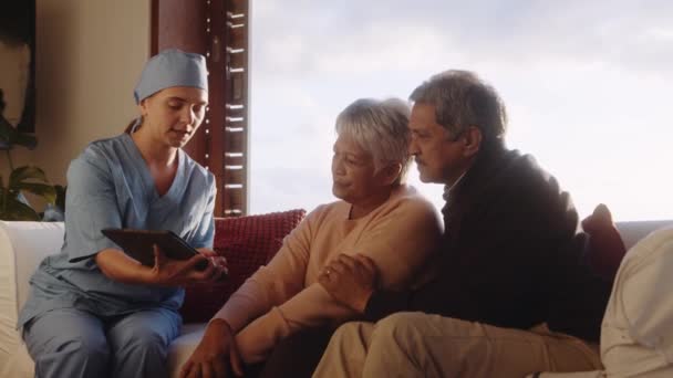 Professionnel médical expliquant le diagnostic négatif au couple âgé dans leur maison sur tablette — Video
