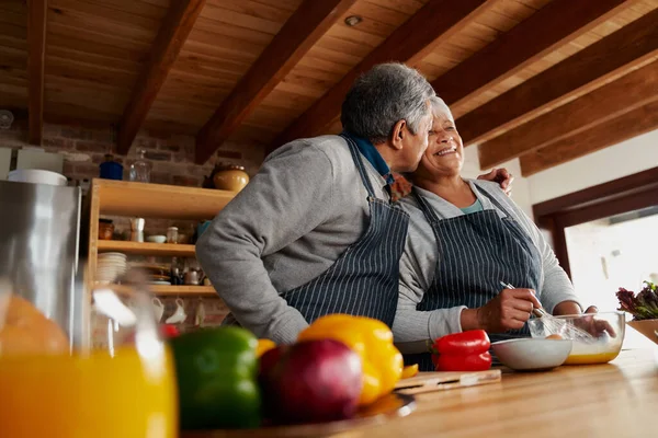 Melez yaşlı çift mutfakta mutlu bir şekilde yemek pişiriyor. Koca karısını yanağından öpüyor, evde sağlıklı bir emekli hayat sürüyor..