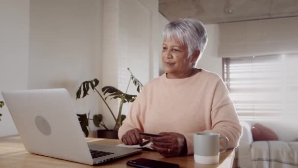 Mujer de edad avanzada multicultural que comienza a hacer compras en línea en el ordenador portátil, utilizando la tarjeta de crédito en casa — Vídeos de Stock