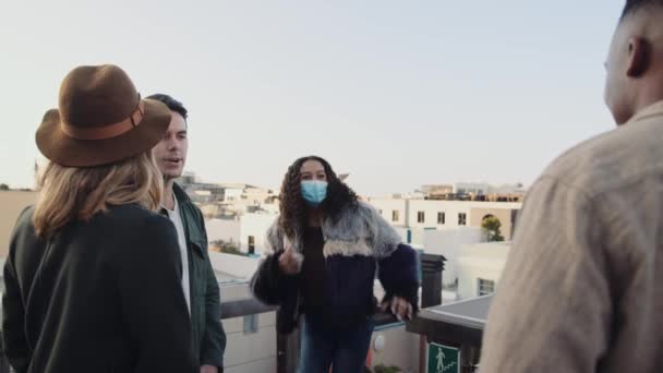 Multikulturelle Frauen schließen sich an und begrüßen eine bunt gemischte Gruppe erwachsener Freunde auf einer Party auf dem Dach. Nimmt Maske ab. — Stockvideo