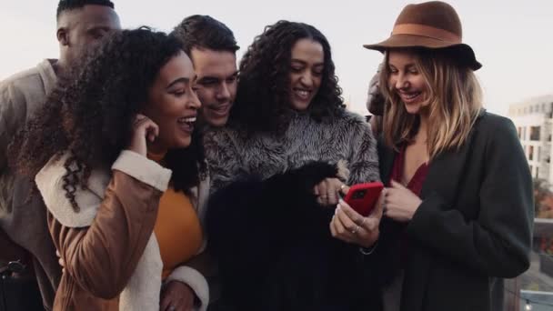Rozmanitá skupina přátel hledí na chytrý telefon smějící se venku na střeše. Vysoce kvalitní 4K záběry. — Stock video