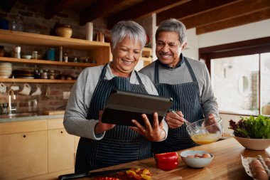 Çok kültürlü yaşlı çift gülümsüyor, modern mutfakta kahvaltı hazırlıyorlar. Mutlu çift evde emekli oldu..