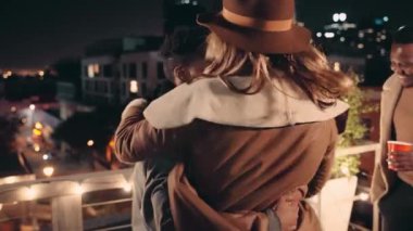 Siyah erkek ve beyaz kadın gecenin bir yarısı çatıdaki bir partide arkalarında şehirle birlikte dans ediyorlar..