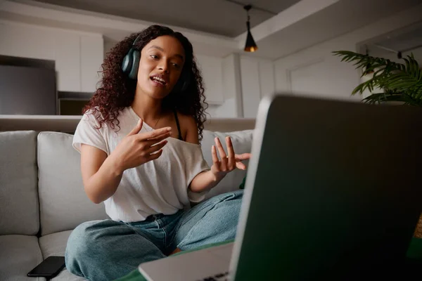 Mulher adulta multicultural em uma chamada em seu laptop explicando com as mãos — Fotografia de Stock