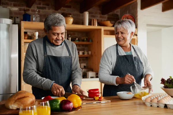 Çok kültürlü yaşlı bir çift modern mutfakta mutlu bir şekilde yemek hazırlıyor. Sağlıklı bir emekli yaşam tarzı..