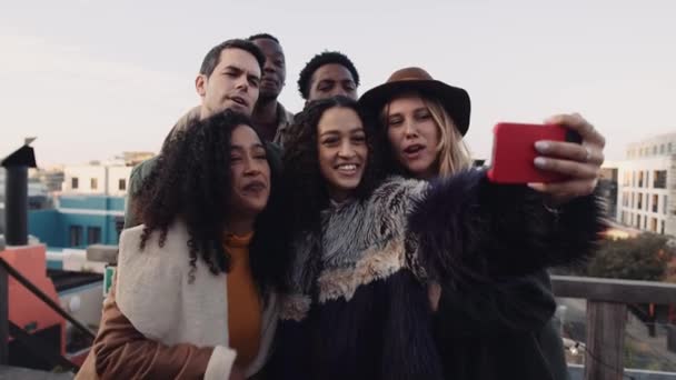 Diverso grupo de amigos tomando una selfie en un teléfono inteligente al aire libre en una azotea. Imágenes 4K de alta calidad. — Vídeo de stock