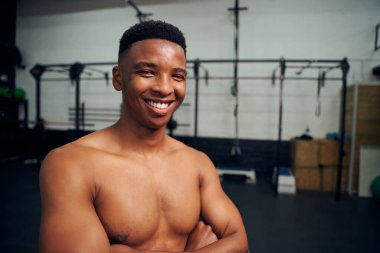 Kollarını kavuşturup kameraya gülümseyen Afrikalı Amerikalı bir erkek. Erkek sporcu spor salonunda egzersiz yaparken mutlu görünüyor. Yüksek kalite fotoğraf 