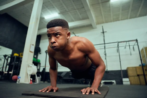 Jovem afro-americano fazendo flexões no ginásio. Raça mista, personal trainer masculino fazendo cross fit dentro de casa. Foto de alta qualidade — Fotografia de Stock