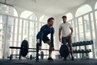 Modern spor salonunda antrenörüyle ağırlık kaldırma özürlü. Koçu tarafından çalıştırılan protez bacaklı bir adam. 