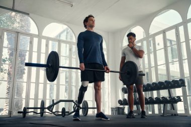 Spor salonunda koçuyla birlikte felçli bir atlet halter. Hocası tarafından çalıştırılan protez bacaklı bir adam. 