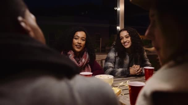 Diverso grupo de amigos charlando, sonriendo y merendando en una fiesta al aire libre en una mesa — Vídeo de stock