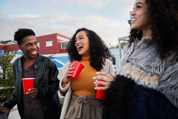 Groupe de jeunes adultes multiculturels debout sur un toit-terrasse en ville. Socialiser, boire et rire avec des amis — Photo