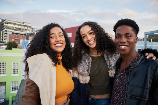Retrato de un grupo diverso de jóvenes adultos multiculturales de pie, sonriendo a la cámara en una terraza en la azotea de la ciudad — Foto de Stock