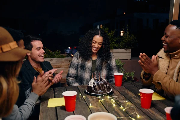 Anniversaire fille rire tandis que le groupe de divers jeunes adultes assis à Boho thème sur le toit fête célébrant avec gâteau. — Photo