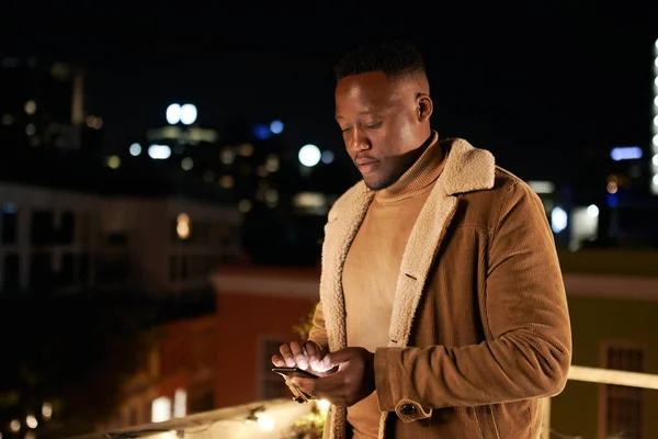 독립적 이고 키크고 잘생긴 흑인 남성 이 옥상 테라스 위에 서서 휴대폰으로 문자를 보내고 있습니다. 시티 케이프의 배경. — 스톡 사진
