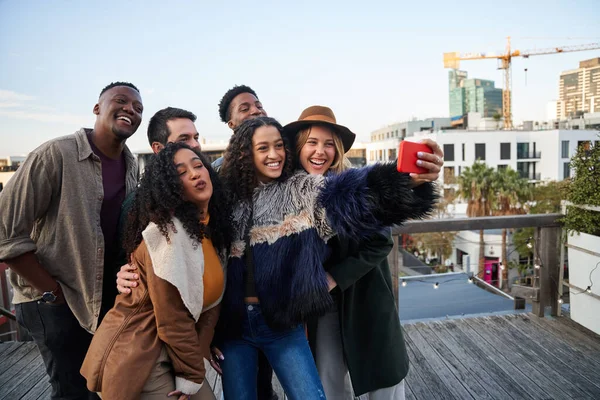 Groupe multiculturel d'amis prenant un selfie lors d'une fête sur le toit. Poser avec de jeunes amis adultes. — Photo
