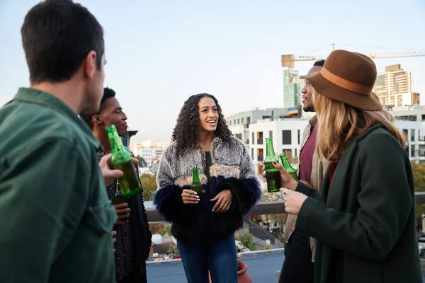 Grupo multicultural de jovens adultos conversando com bebidas na varanda de um terraço no último piso da cidade. — Fotografia de Stock