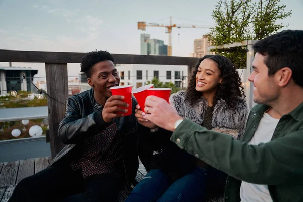 多文化の若い大人のグループは、トーストを作りながら笑顔。市内の屋上パーティーで楽しい時間を. — ストック写真