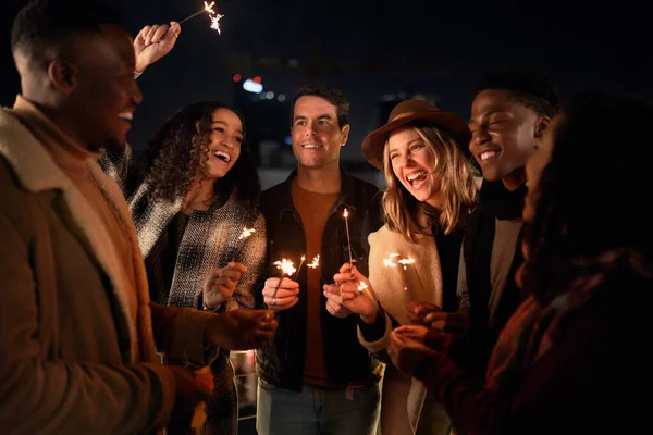 Divers groupes d'amis souriant ensemble à une fête sur un toit-terrasse. Vie nocturne en ville, Éclairage Sparklers — Photo